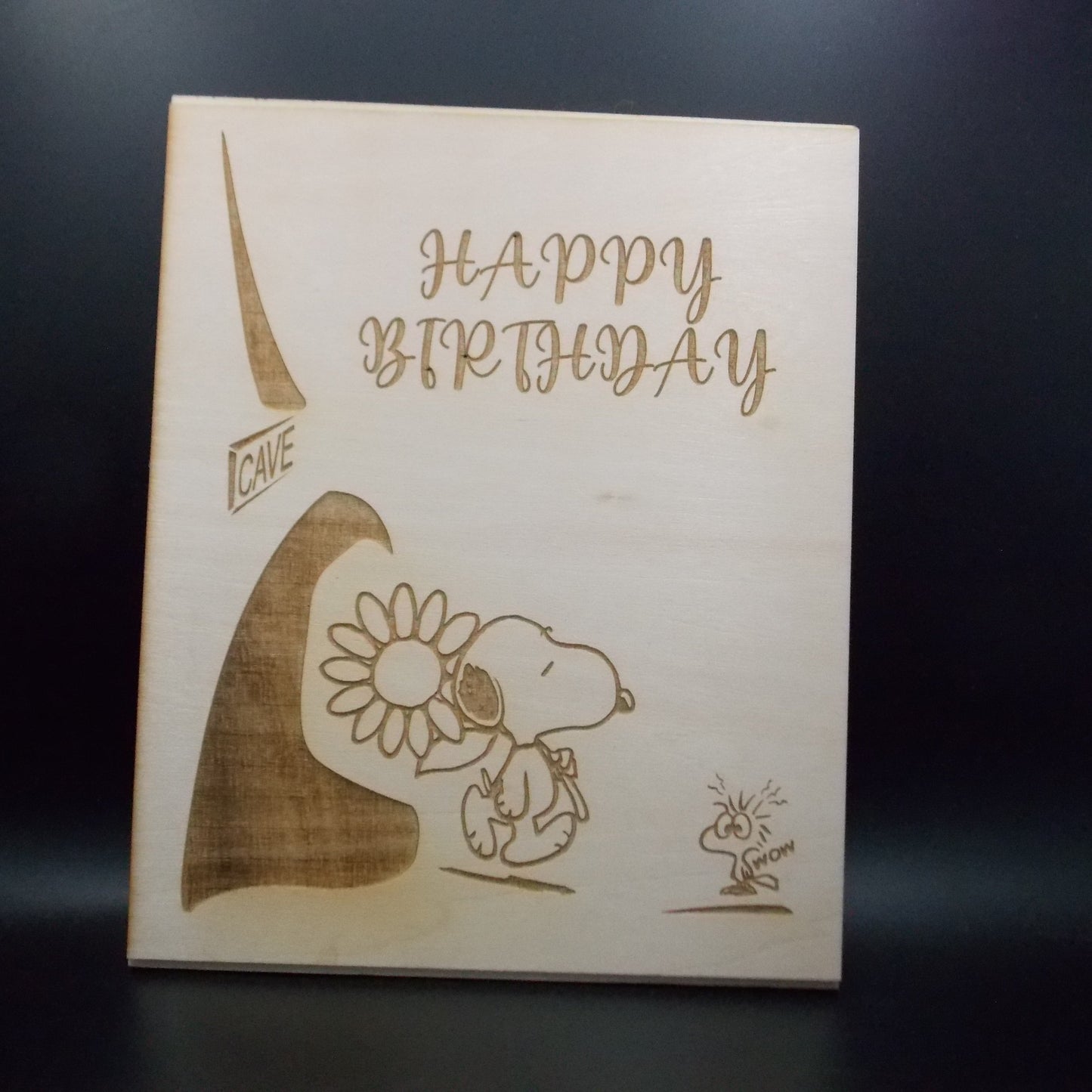 Wooden plaque with engraved birthday message and cartoon characters on a dark background