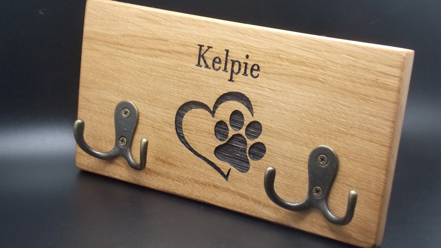 Wooden plaque with metal hooks and engraved paw print design on a dark background